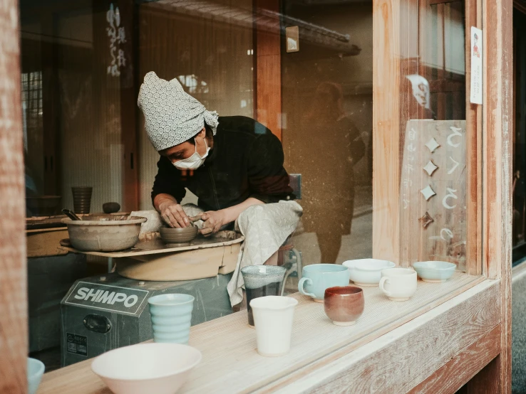 a woman is making clay bowls with a hammer