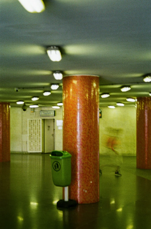 an orange and green trash can is in the middle of a warehouse