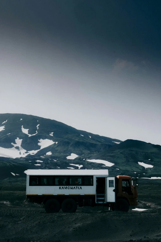 a truck parked in a parking lot with snow covered hills behind it