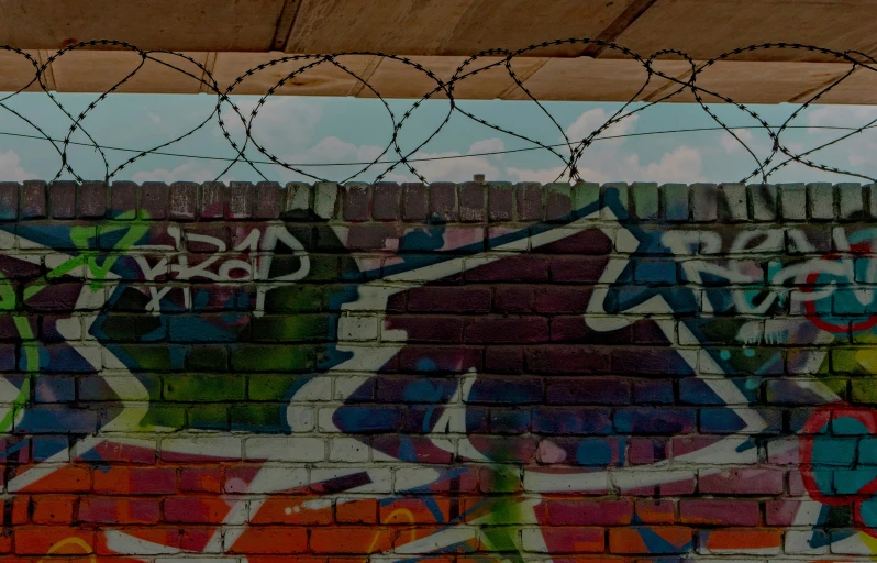 a wall with graffiti and razor wire in the foreground