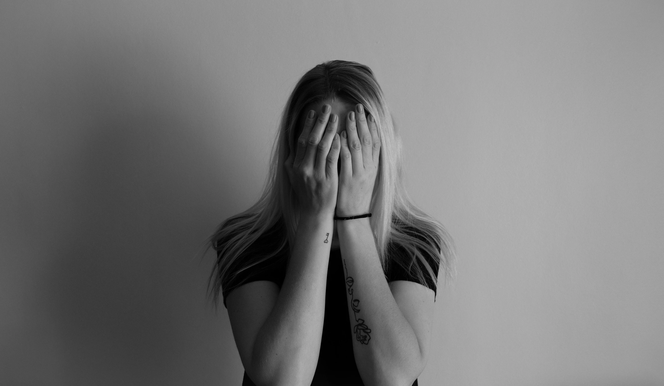 a woman covers her eyes with hands in black and white