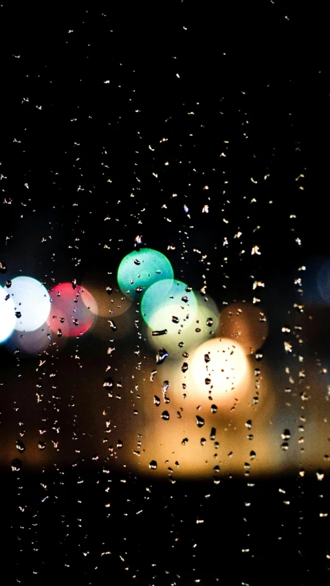 a window with raindrops at night with street lights in background