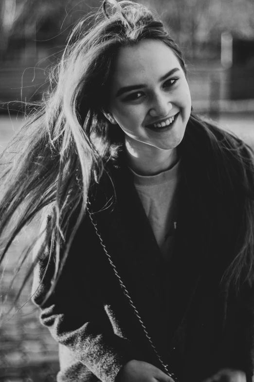 an adorable smiling young lady with her hair in the wind