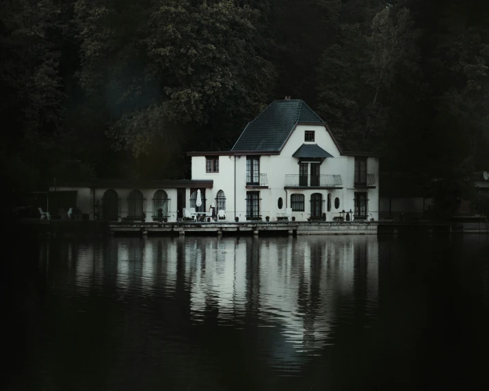 a white house on water surrounded by trees