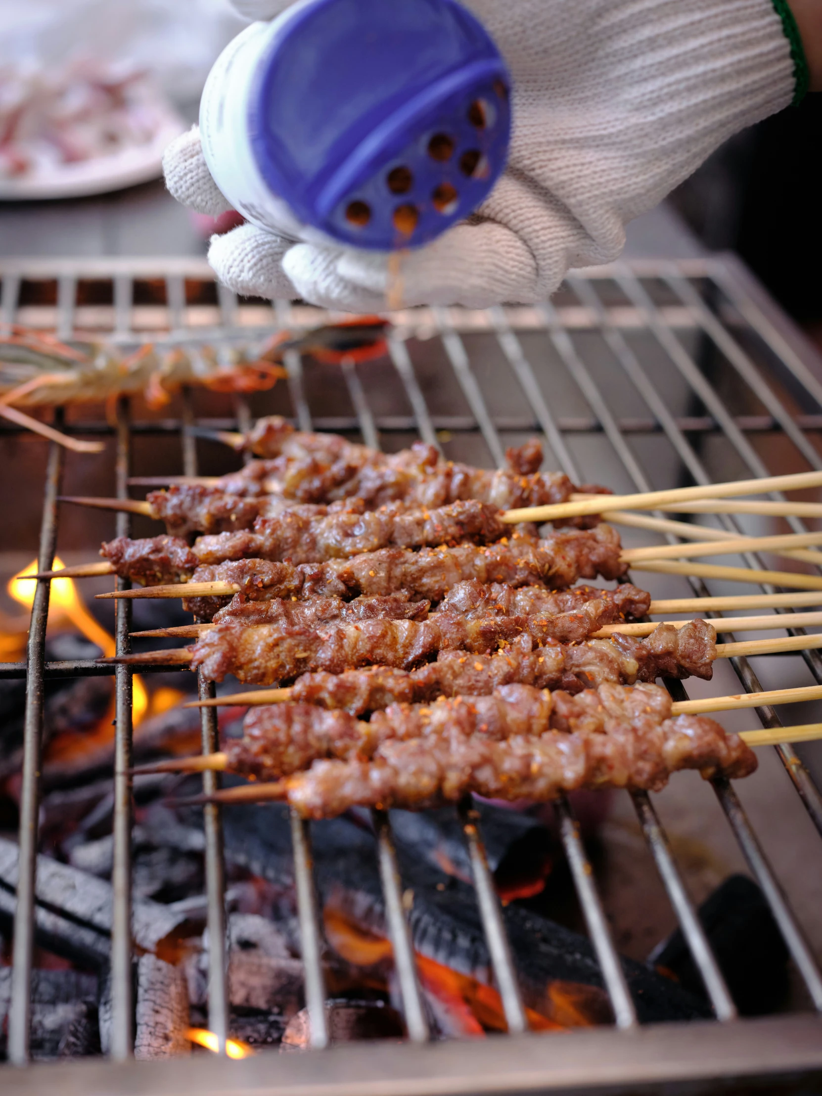 a person cooking meat on skewers on the grill