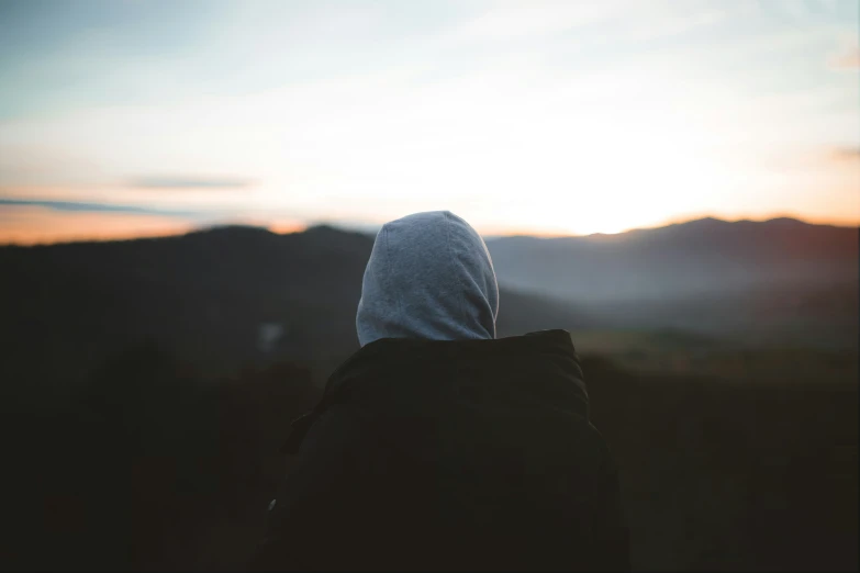 a man stands in the sun while watching the mountain range