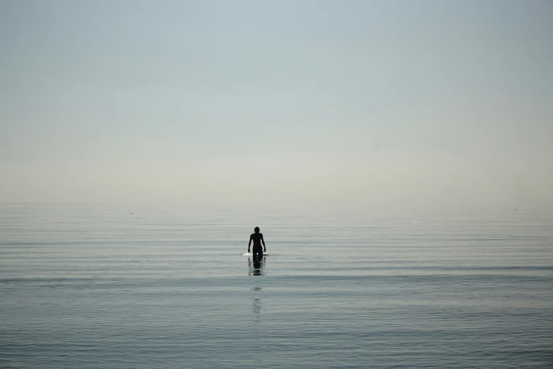 man on surf board standing in calm ocean waters