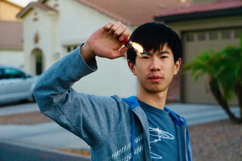 a man holds a lighter in front of his head