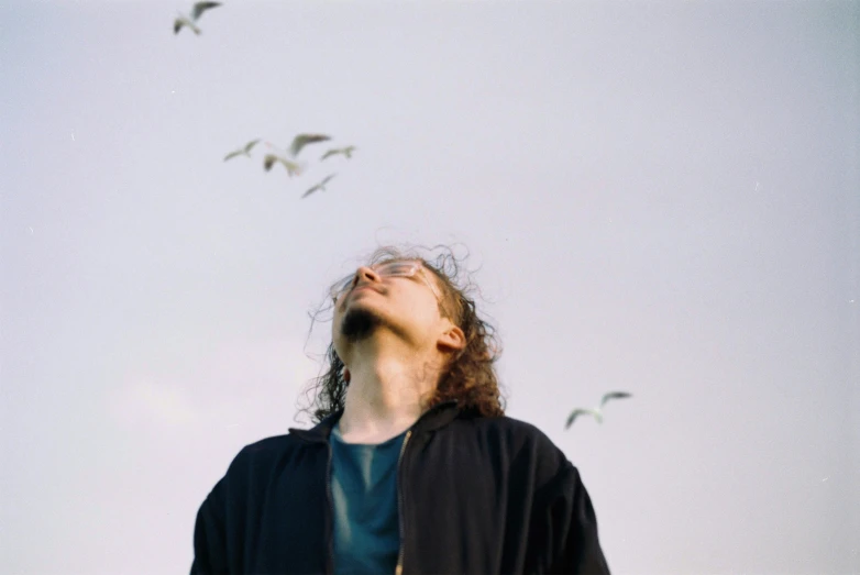 a man stands in front of a flock of birds