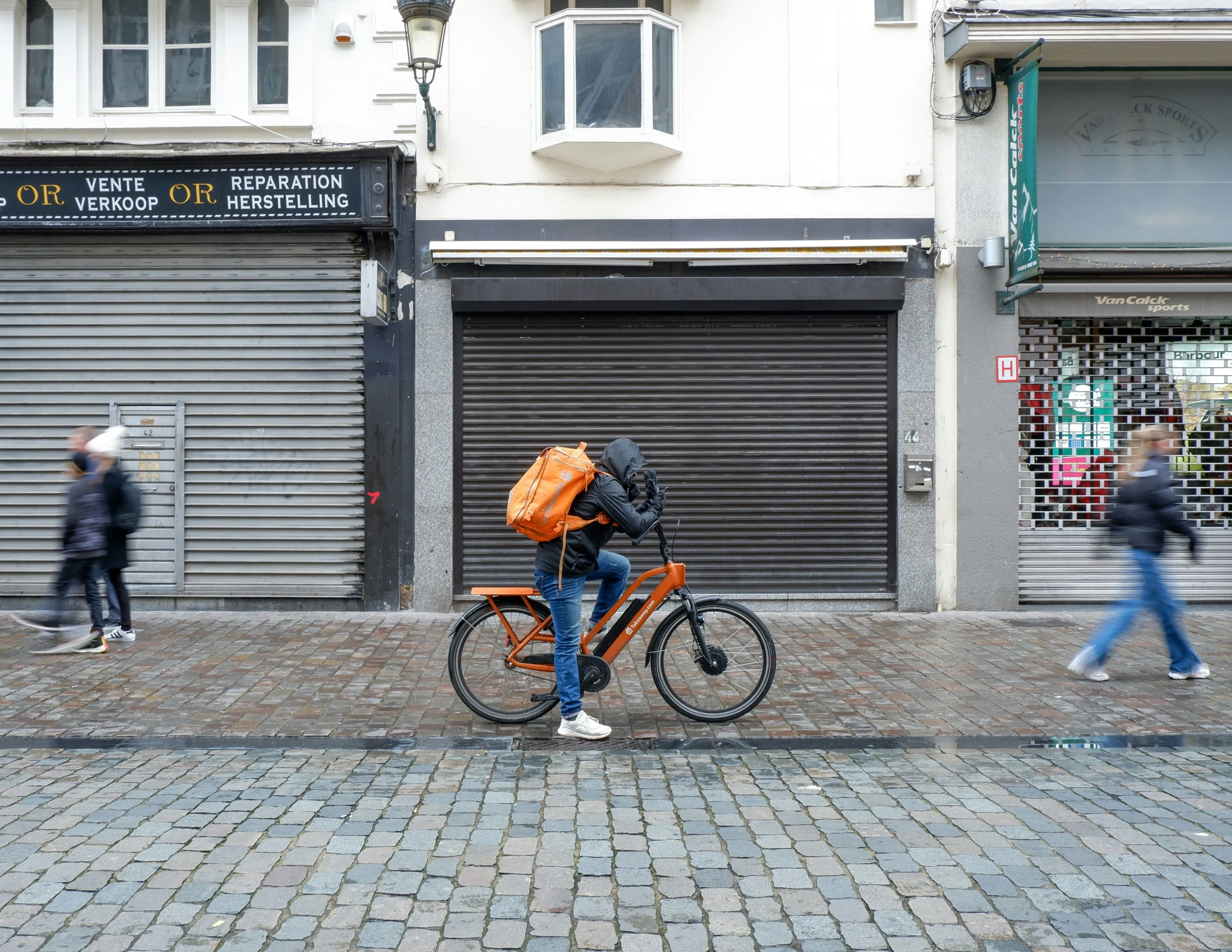 a man in orange backpack on bike and people walking
