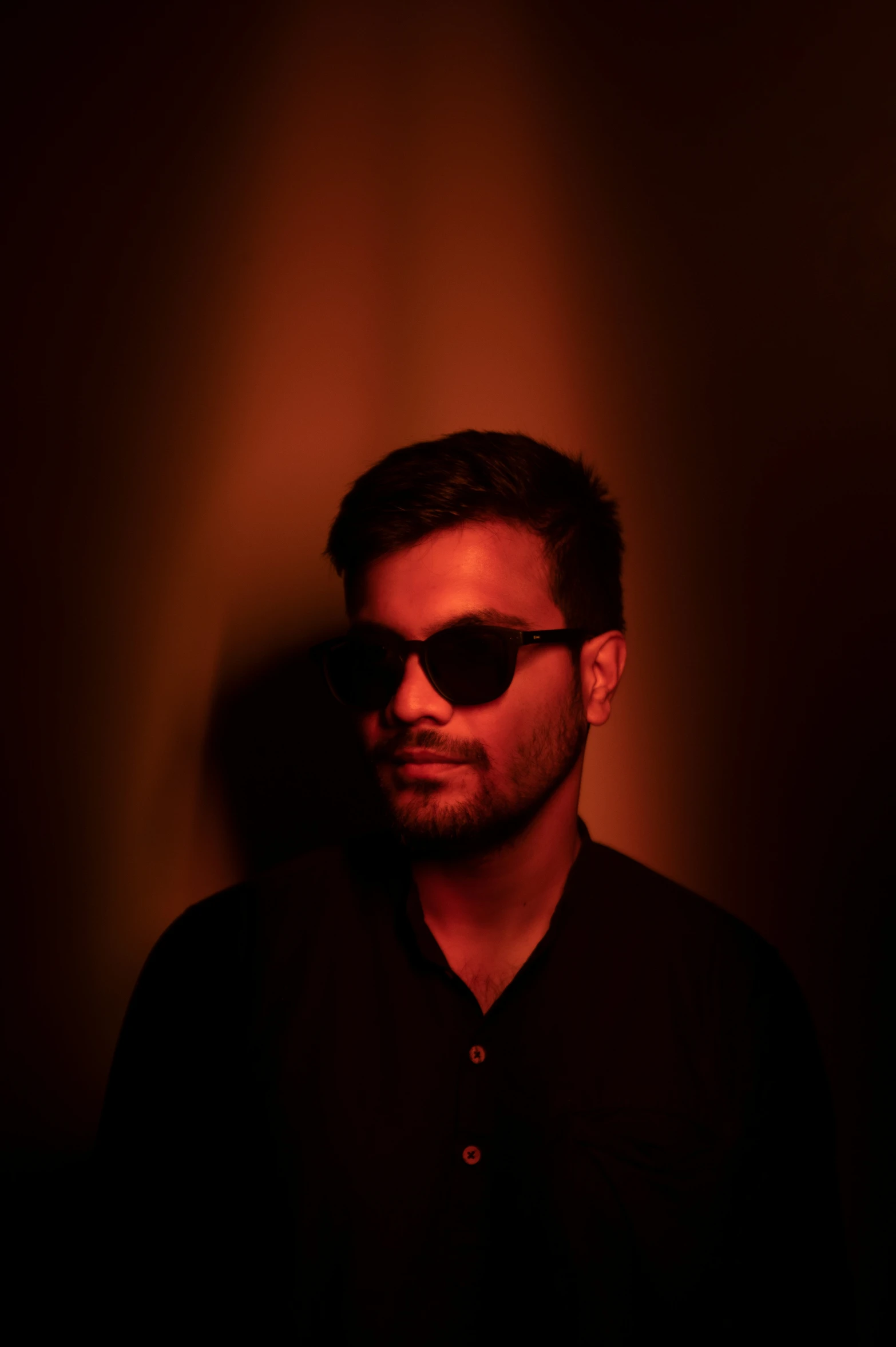 a young man with dark sunglasses looks into the camera