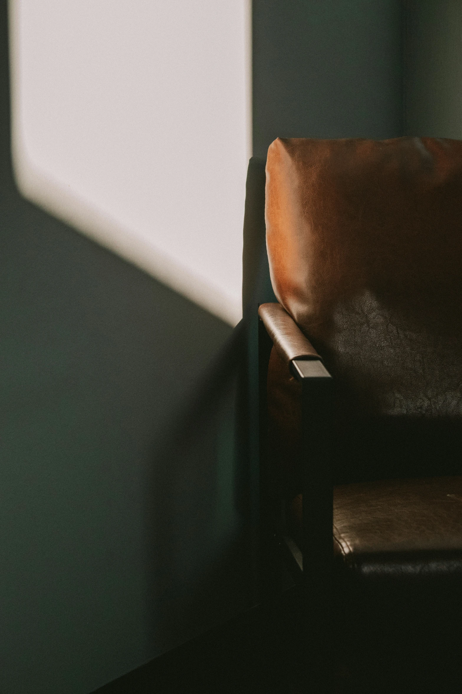 a brown leather chair with sunlight streaming in the background