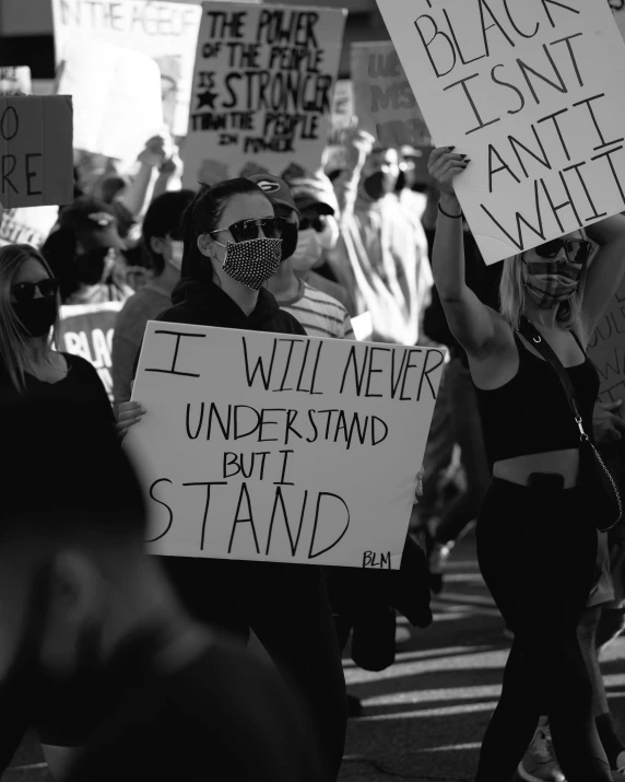 many people with faces painted hold up protest signs