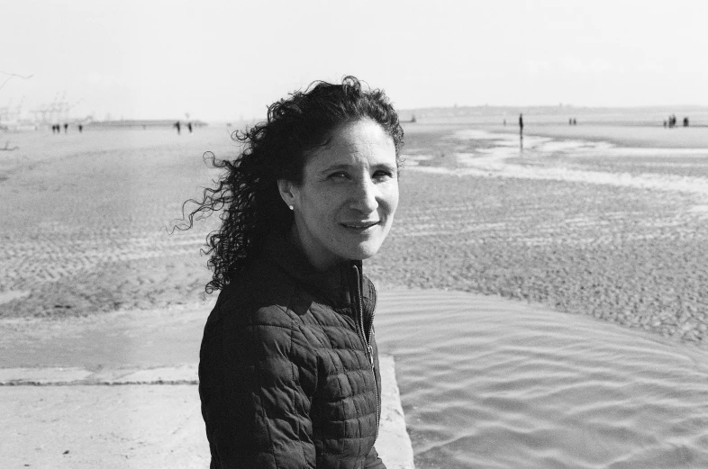 a woman standing on the beach holding onto her surfboard