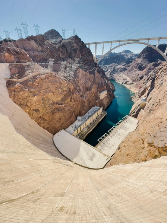 a large river running past a bridge surrounded by mountains