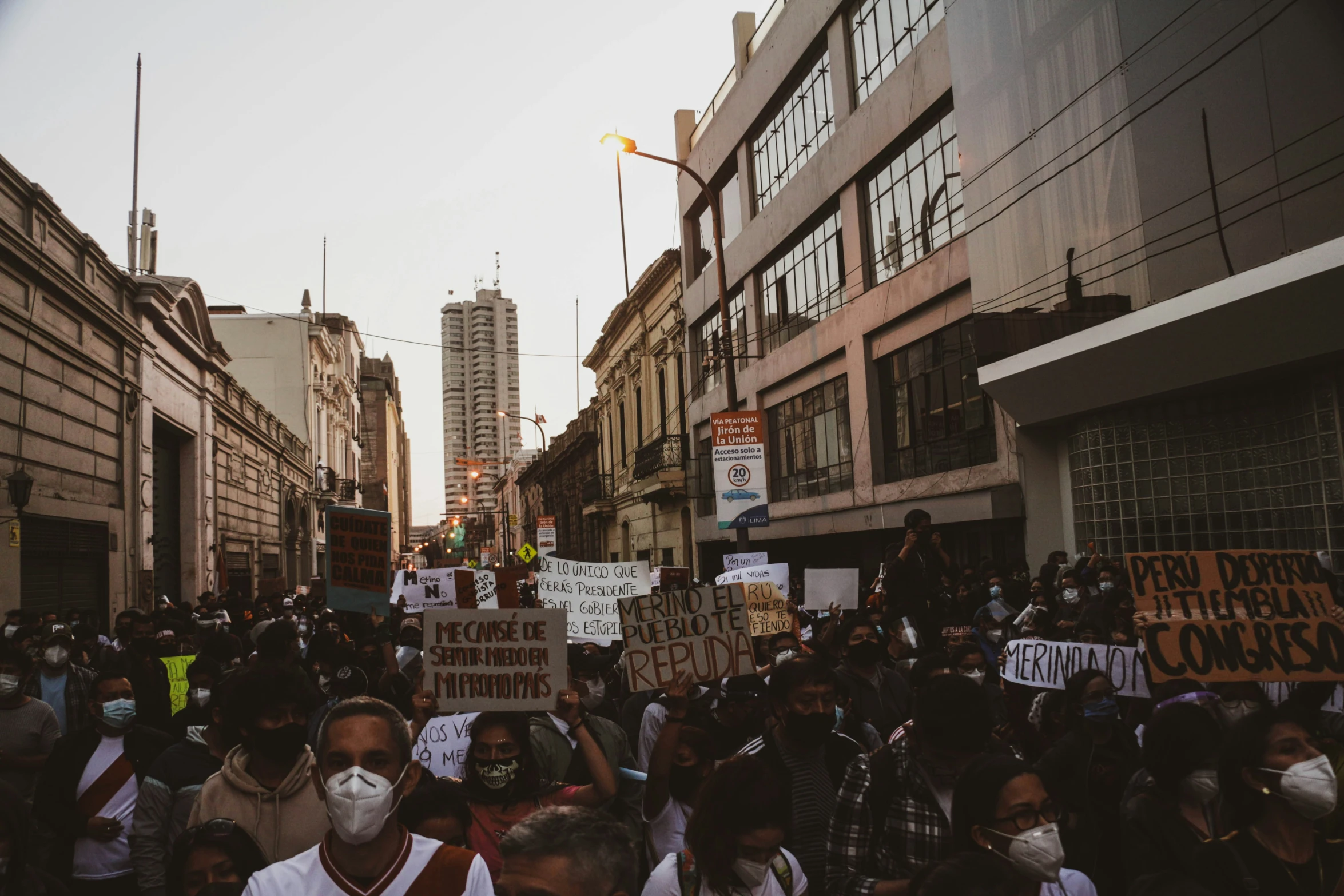 a crowd of people in street with signs and buildings