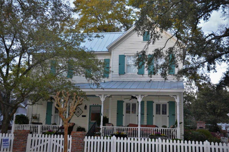 a white house with blue tin roof and picket fence