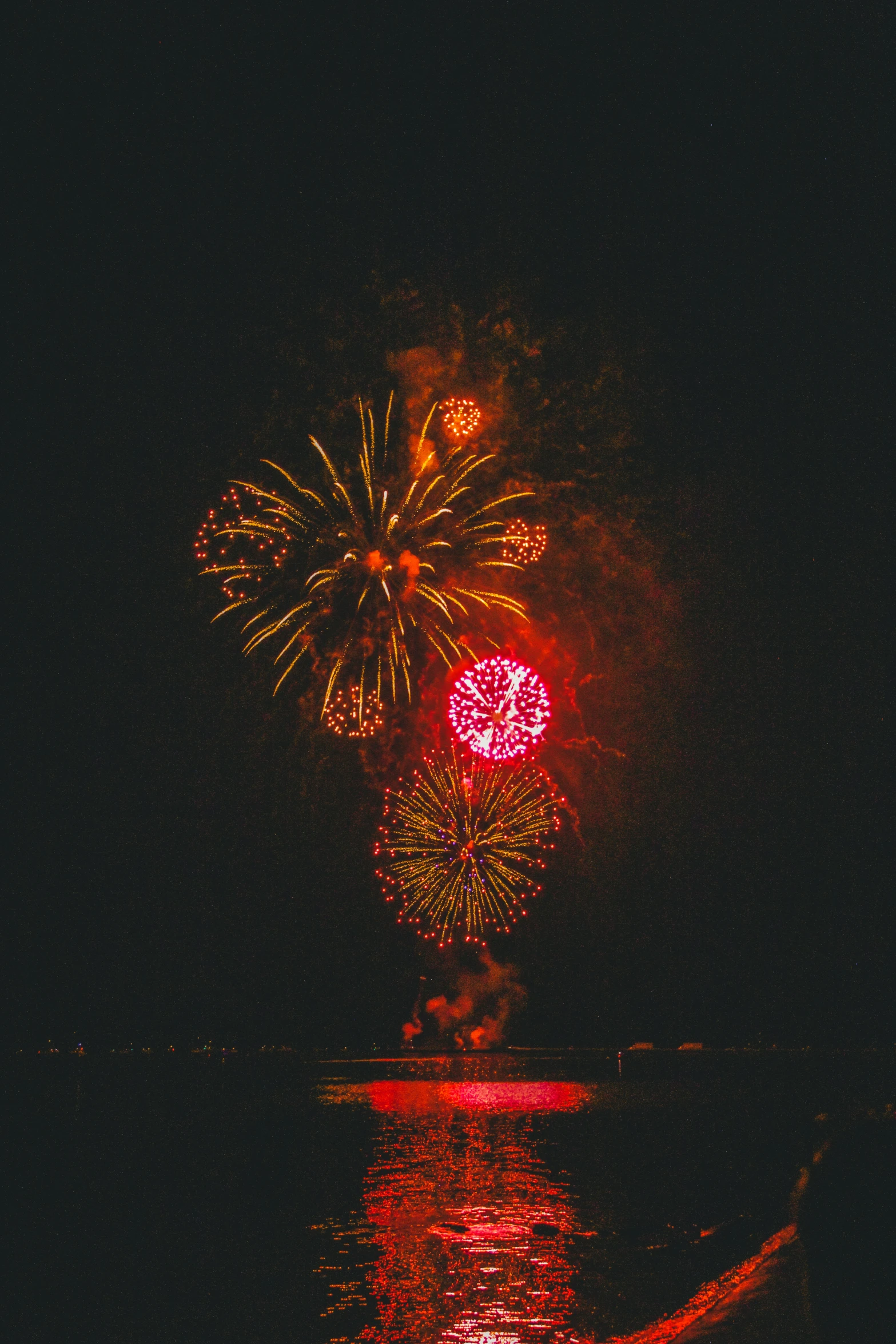 brightly colored fireworks reflecting in water during night