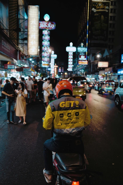 a man on the back of a motorcycle in the middle of a city at night