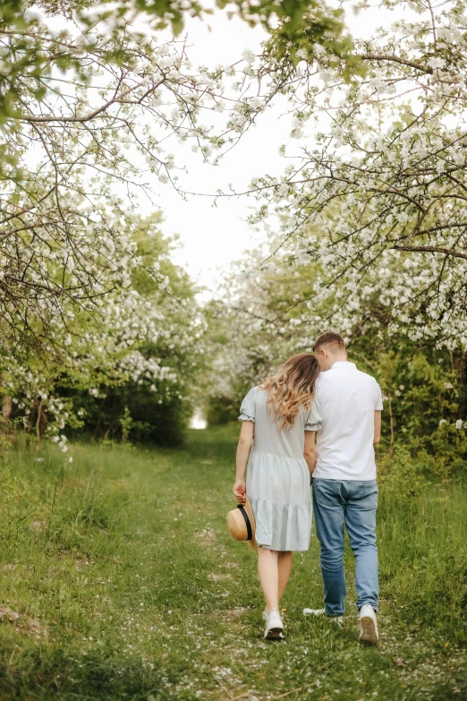 a couple is holding hands while walking through the woods