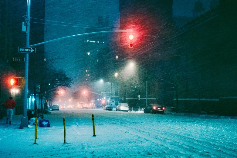 cars on snowy street near traffic light in urban area