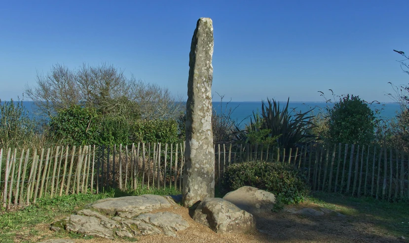 a stone sculpture sitting in front of a fence