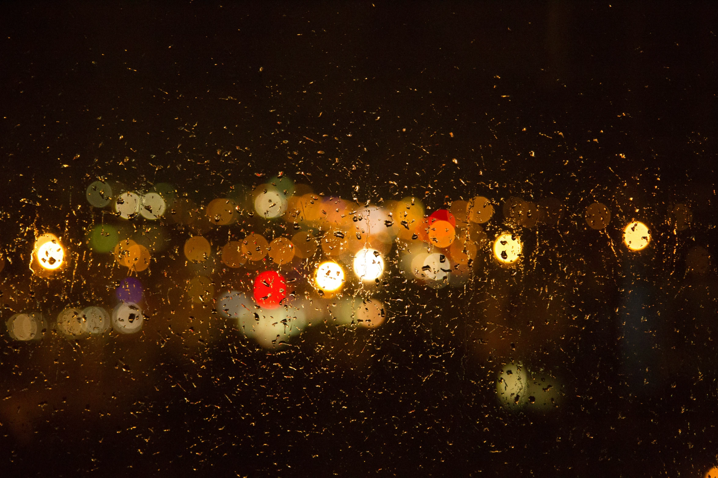 the lights on the street are all reflecting in the wet window