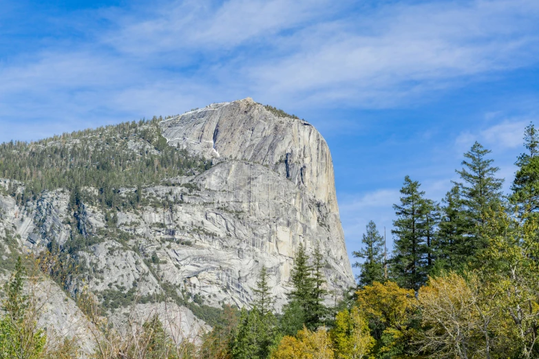 mountain with trees surrounding it under a blue sky