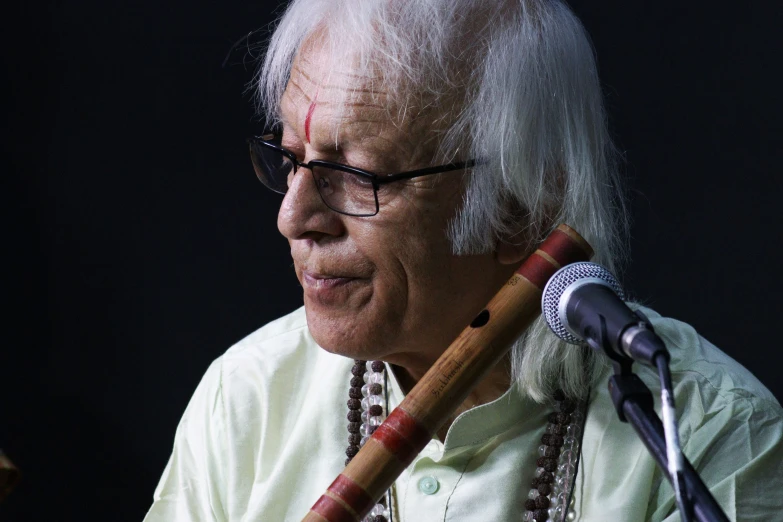 an older man with glasses holding a guitar