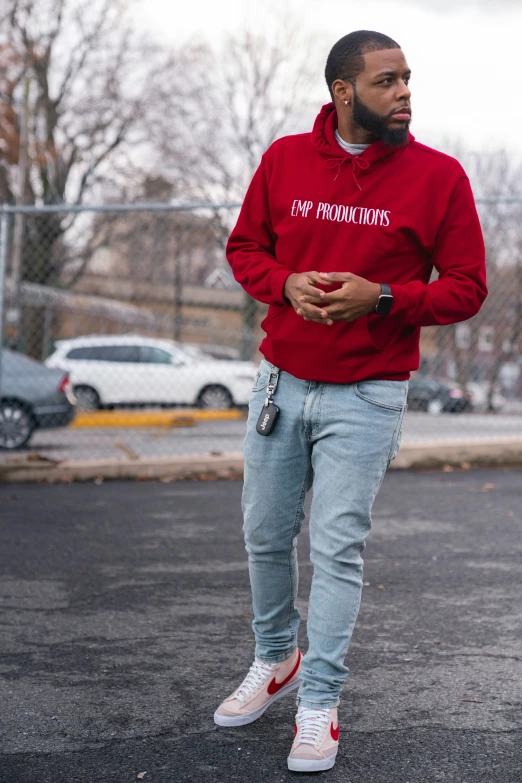 a man in red sweatshirt and jeans wearing a pair of blue ripped jeans with red and white lettering on them