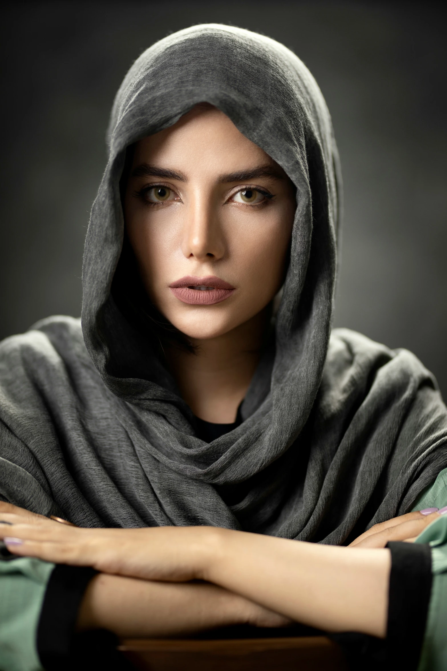 a woman with her arms crossed, wearing a hooded cloak
