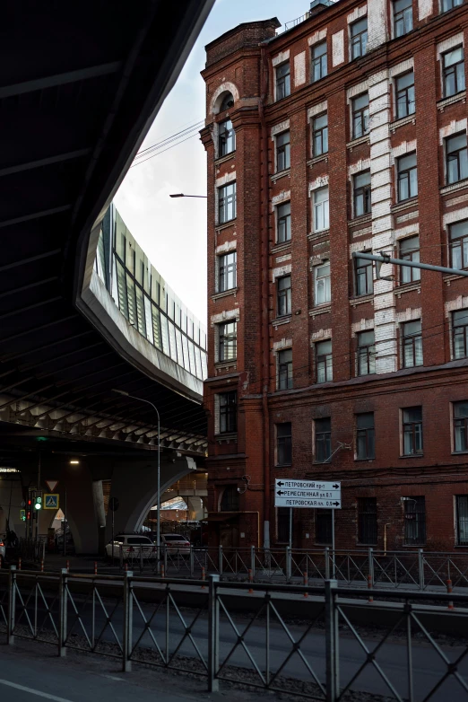 two people stand on a bridge next to a large brick building