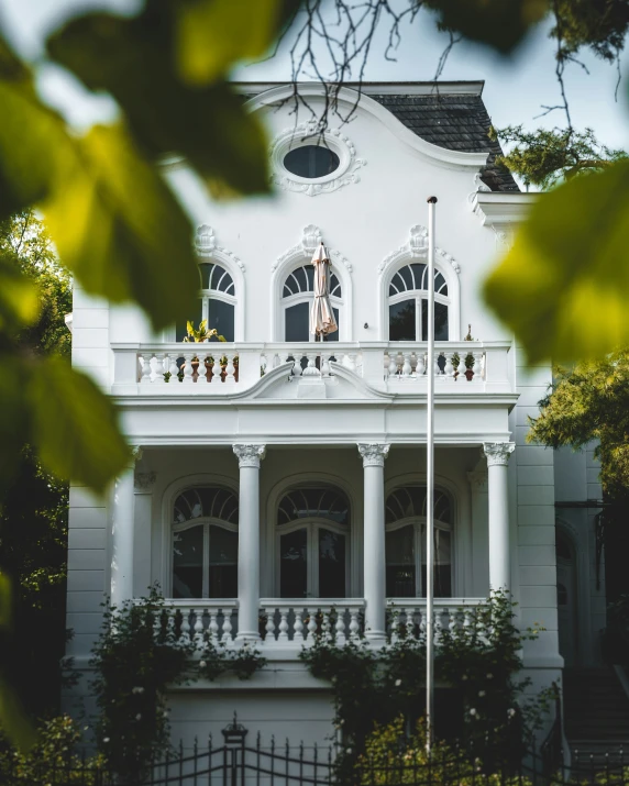 a view through the leaves of trees to a large white house