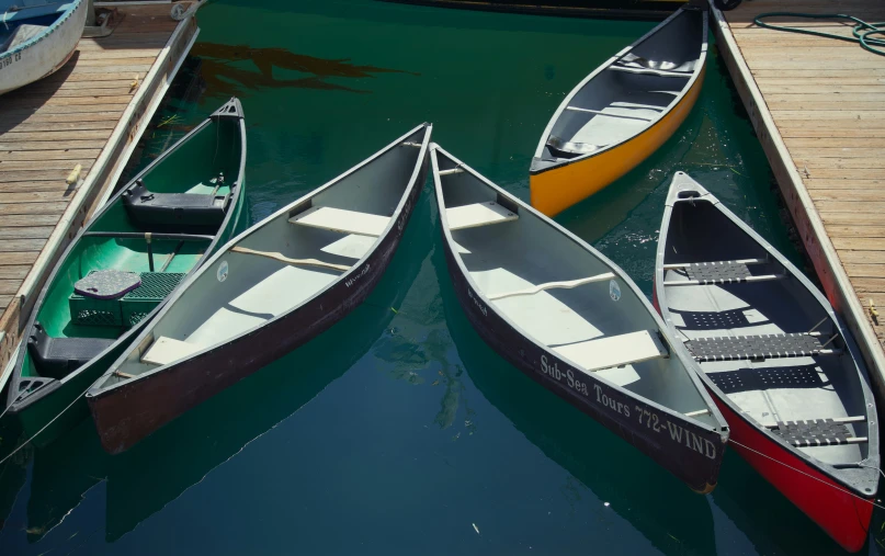 three canoes are tied to a dock next to the water