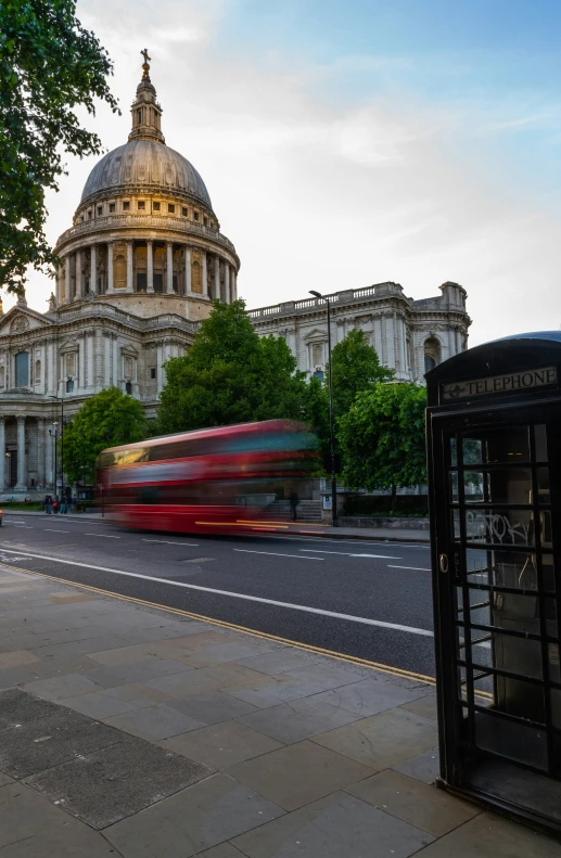 a red bus rides past a big building