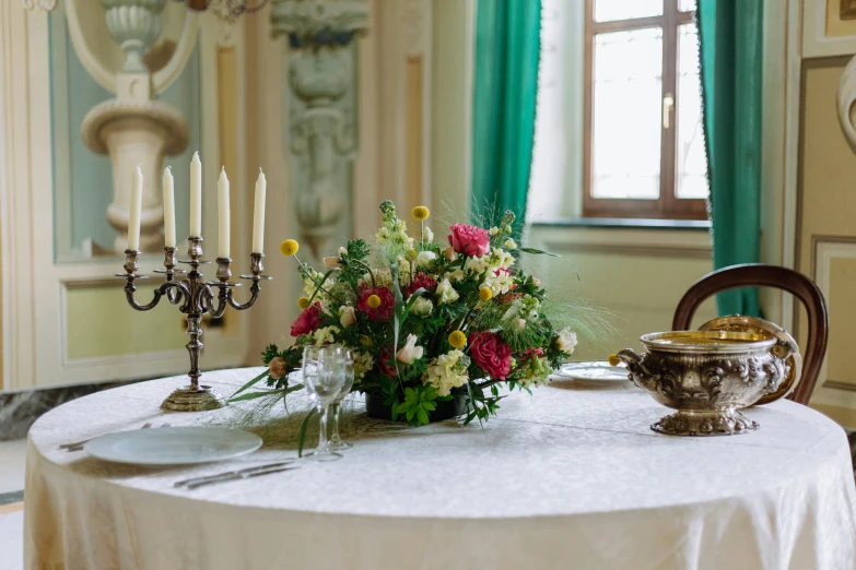 a table with a candle holder, vase and several flowers on it