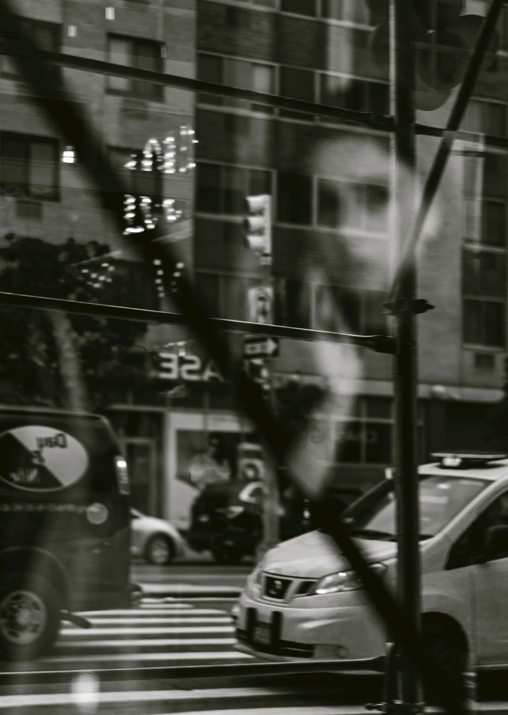 a street view from behind a fence of cars driving in front of buildings