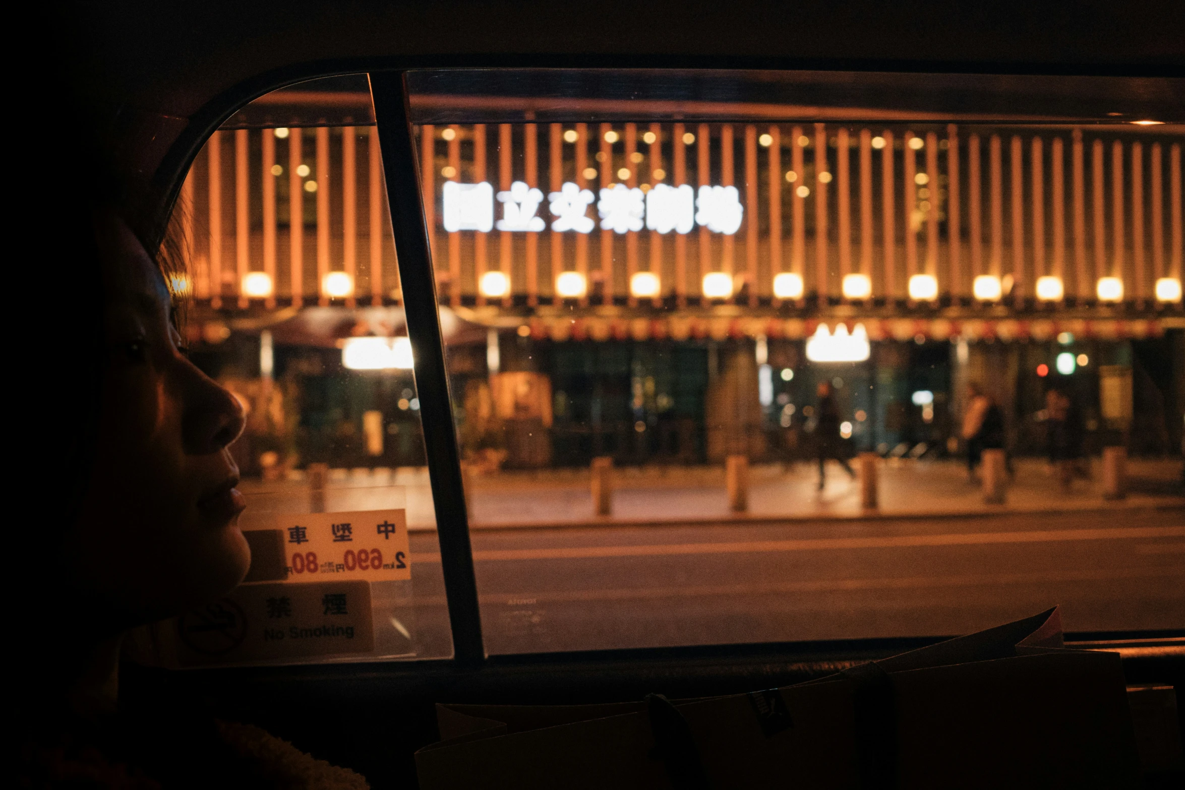 a person sitting in a vehicle outside a building at night