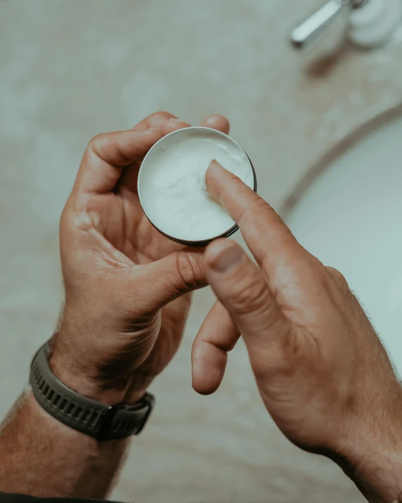 a man holding a cup in his hand near a sink