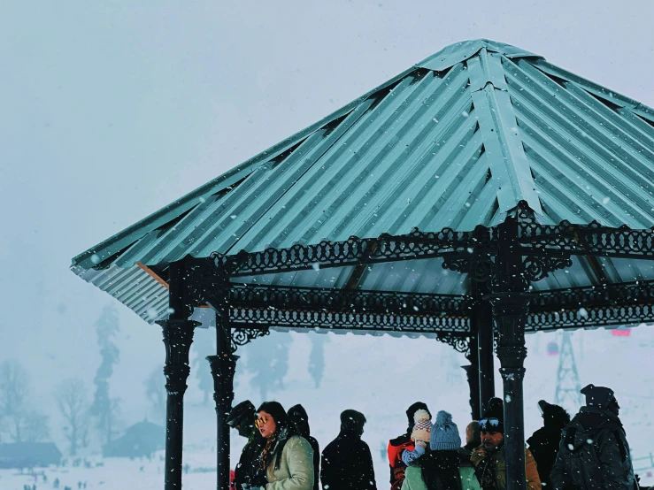 people gather under an ornate pavilion with snow on the ground