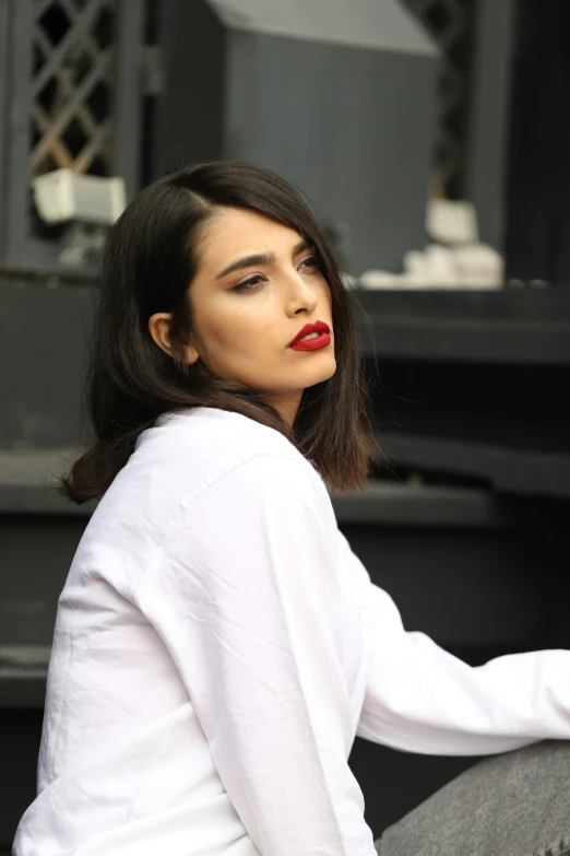 a woman with red lipstick sitting outside