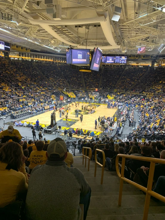 a large crowd watches a game in a college basketball stadium