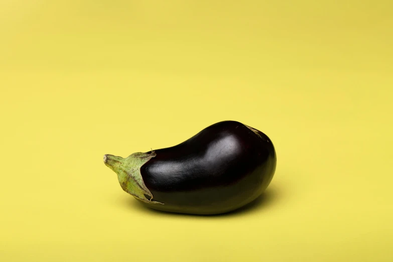 an eggplant sitting on top of a yellow surface