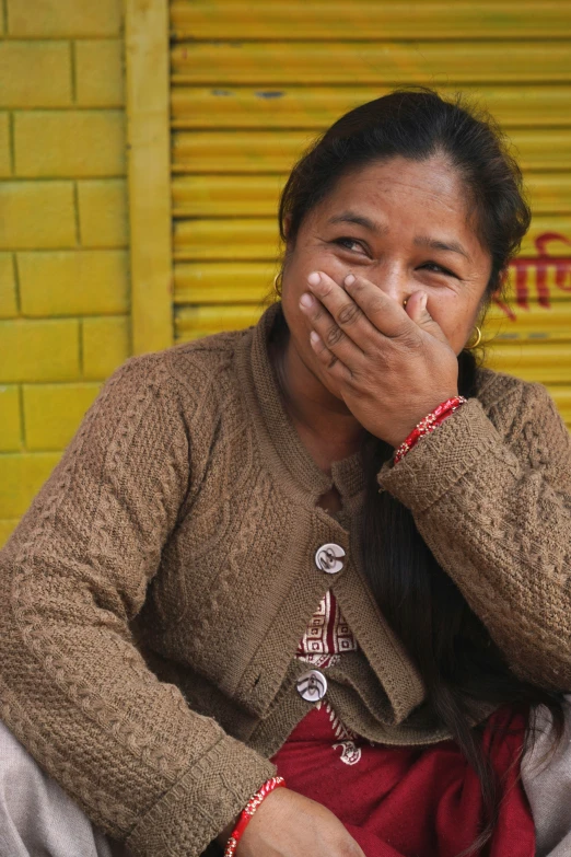 an indian woman covers her mouth with her hands