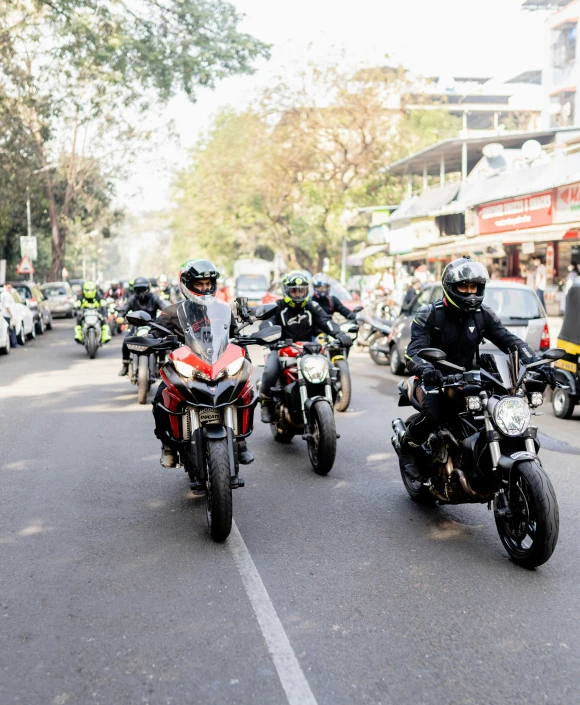 a number of motorcyclists riding down a street