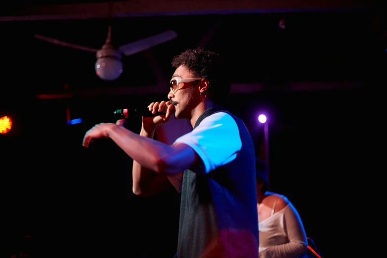 man in sunglasses singing on stage with a microphone