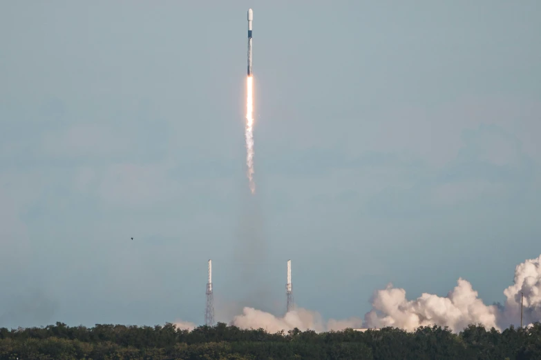 a rocket takes off in the sky above trees