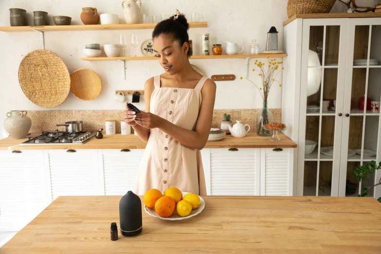 the woman stands in front of the plate of fruit and uses her phone