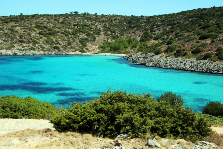 clear blue water and green vegetation around an area of rocky cliff formations