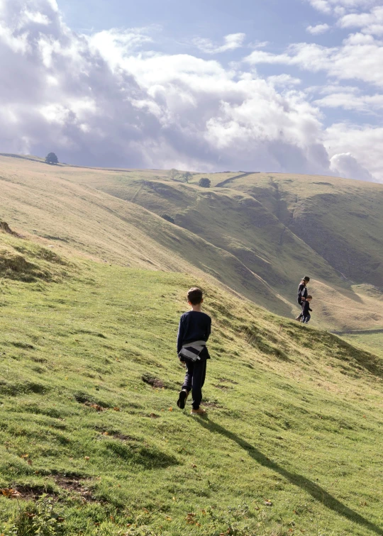 two men standing in a grassy open field on a hill